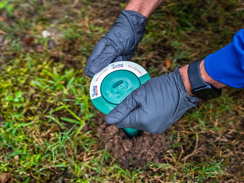 termite control tech checking a bait station