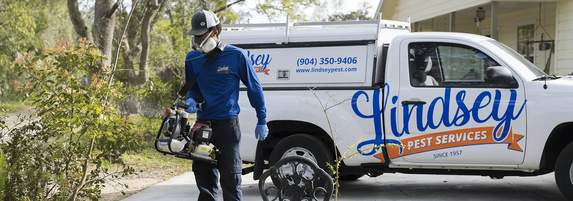 a pest control technician spraying a bush outside of a jacksonville beach home