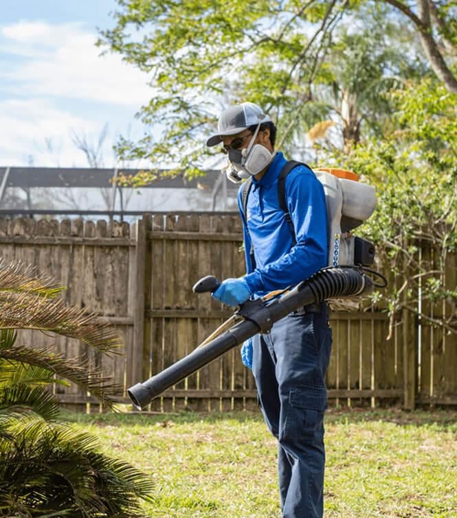 a technician spraying shrubs outside of a jacksonville home for mosquitoes