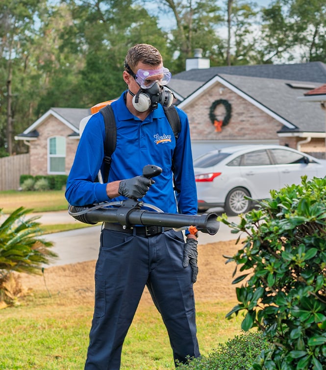 a technician spraying shrubs outside of a jacksonville home for mosquitoes