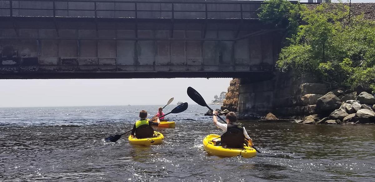 Two kayakers pass underneath a railroad bridge