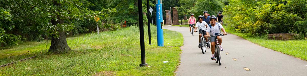 Two children ride their bikes on a paved trail.