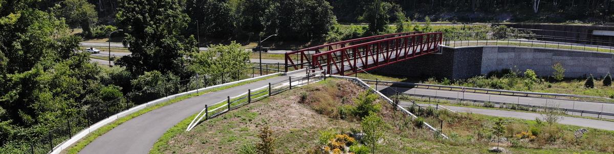 A paved multi-use path curves to reach an overpass