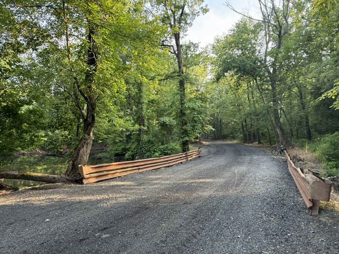 Meadow Road at Goff Brook, facing south. At the bend in the road, a culvert over Goff Brook is marked by two guardrails (Credit: Alan Baglia)