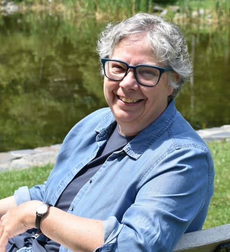 woman with gray hair wearing glasses and a blue shirt