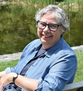 woman with gray hair wearing glasses and a blue shirt