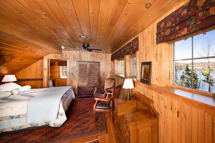 A bed and two chairs in a wood paneled room