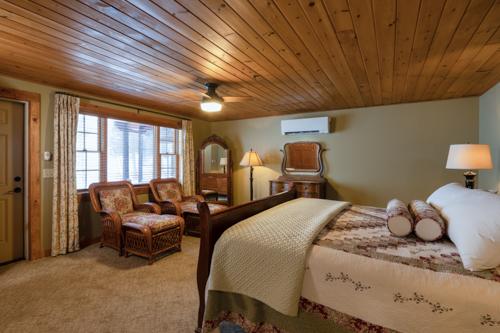 A bed and two chairs in a beige painted room