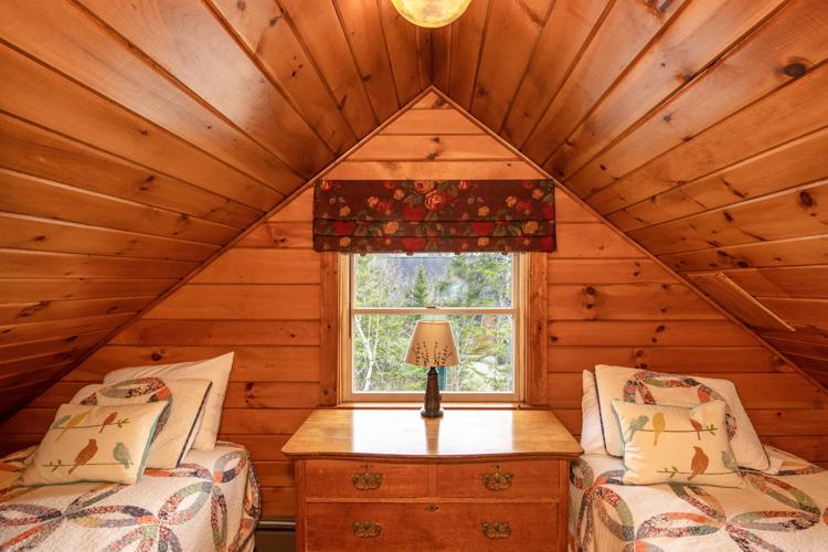 Two beds with a dresser in between with a window above