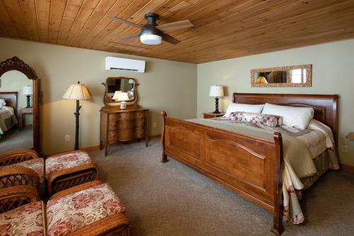 A bed, two chairs, and a dresser in a beige painted room