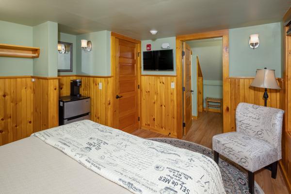 A bed, chair, mini-fridge, and a television in a green room