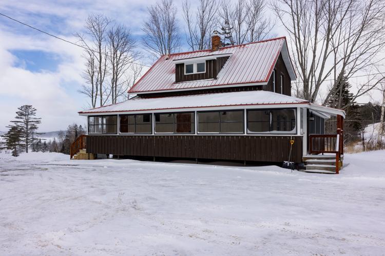 A snow covered building with a red roof and brown paint