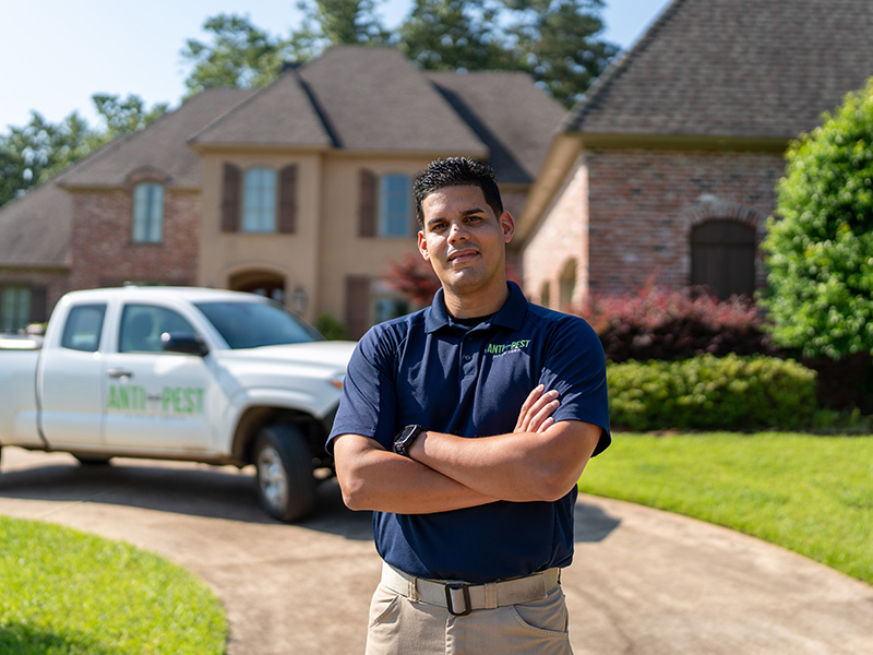 pest technician in front of a home