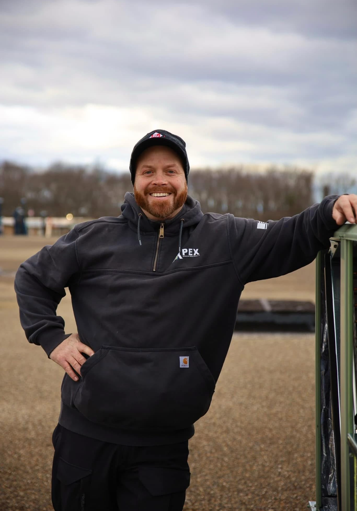Smiling Man leaning on a fence