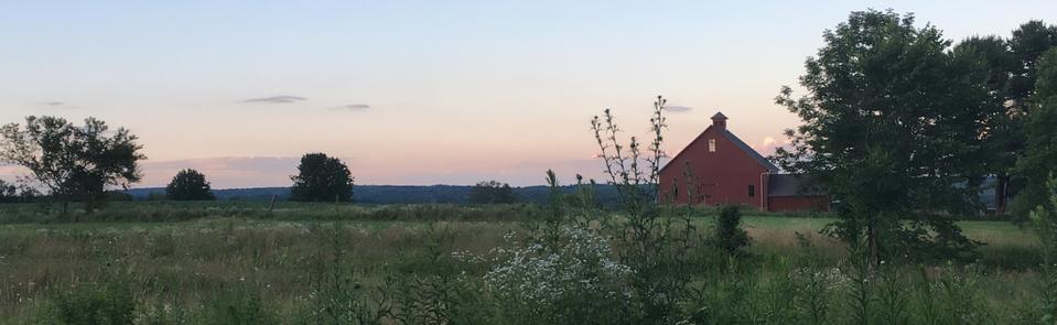 A red barn in the distance at sunrise.