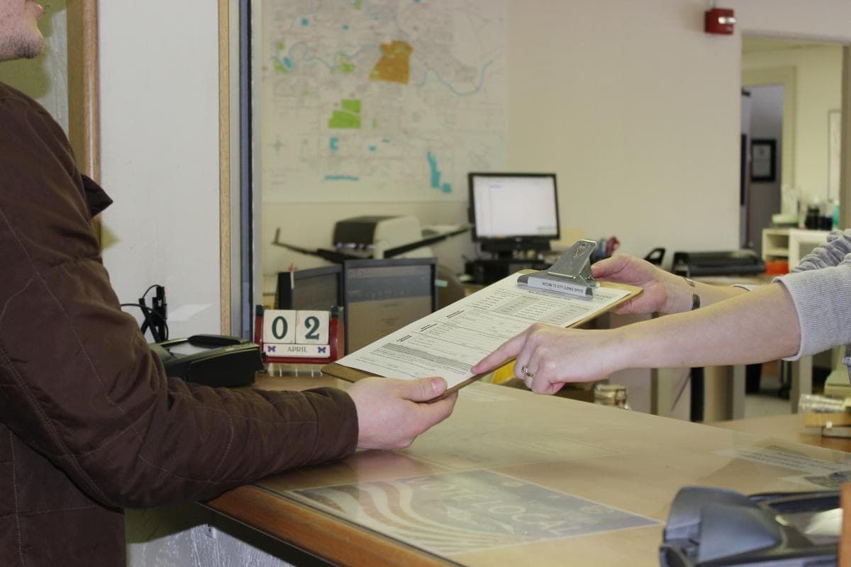 Person handing another person a clipboard
