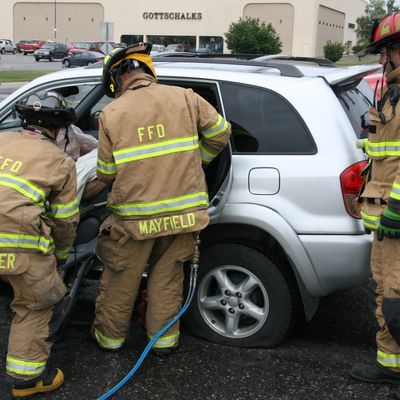 Three firefighters in front of a car