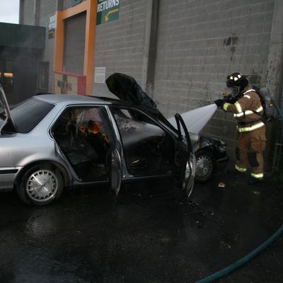 Firefighter spraying car with water