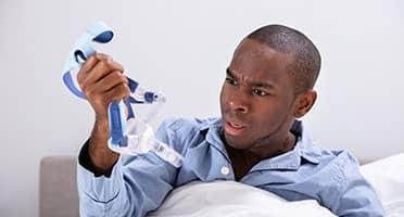 man getting ready to go to sleep with cpap machine