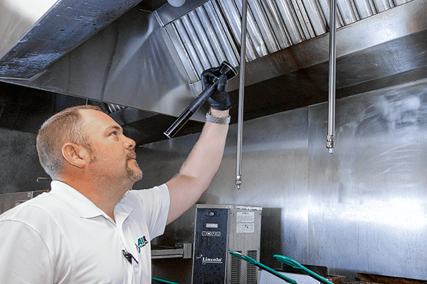a pest technician inspecting the inside of a commercial kitchen