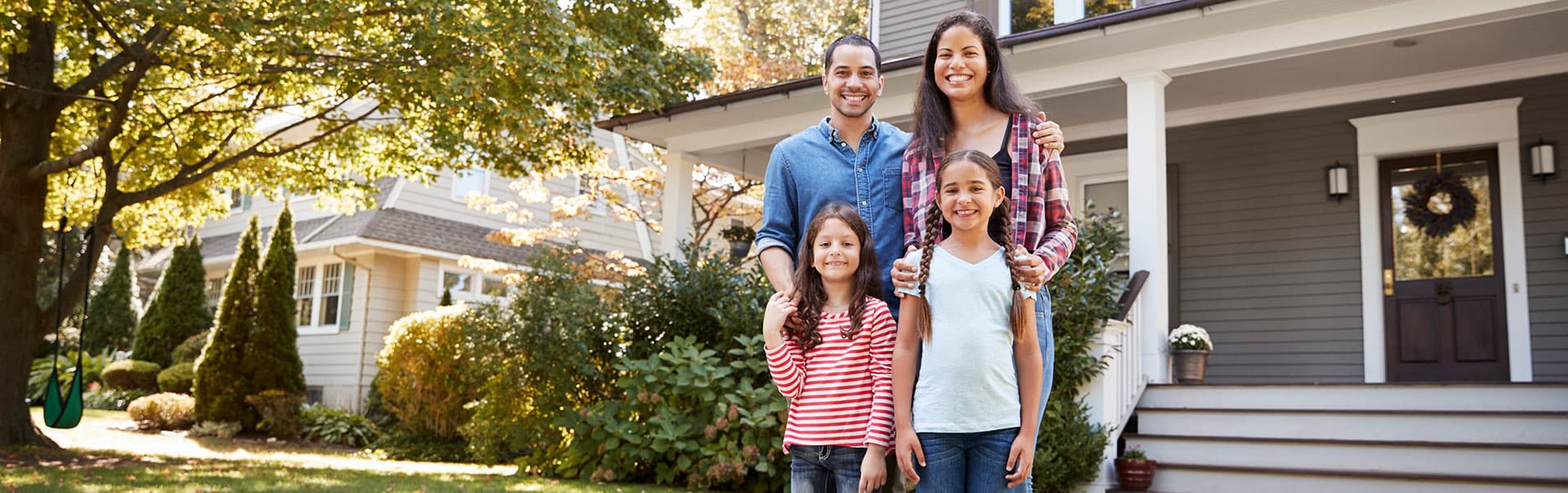 A happy family relaxing on the front porch of a well-maintained suburban house