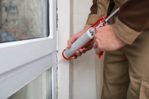 A man caulking a window