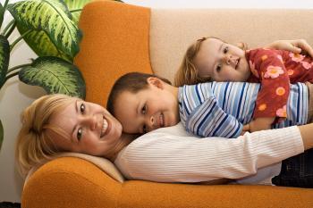 A woman laying on a couch with two children on her