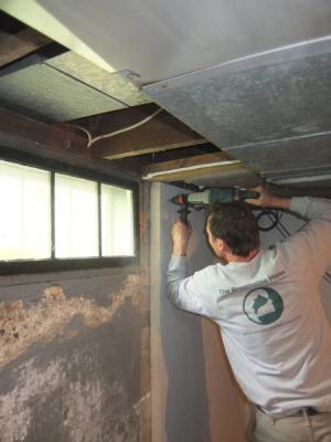 A man installing an insulation sheet in a basement