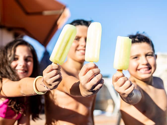 kids enjoying popsicles by the pool summertime