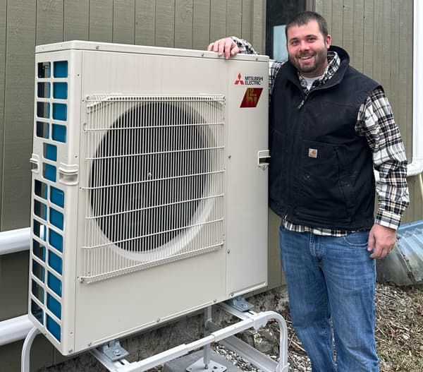 Nathan Bolduc standing next to an installed heat pump