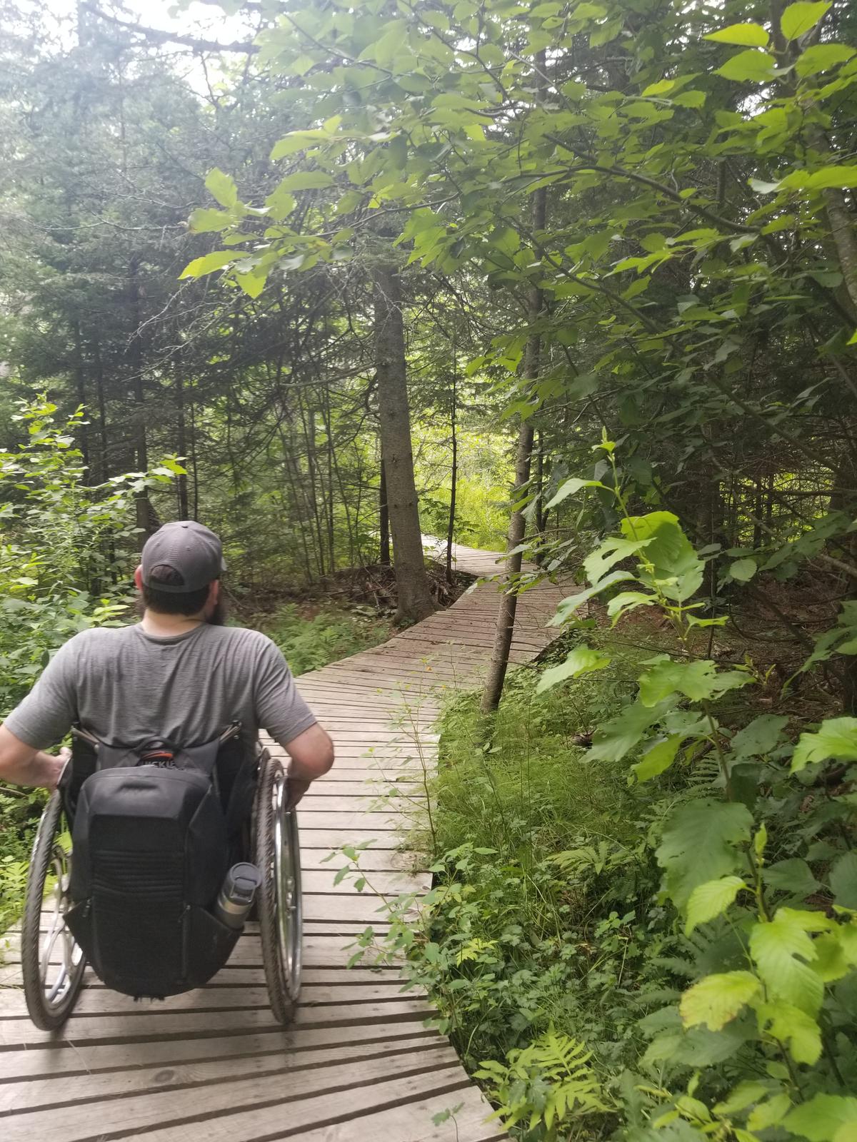 Enock crossing another boardwalk through the woods. Photo credit: Enock Glidden