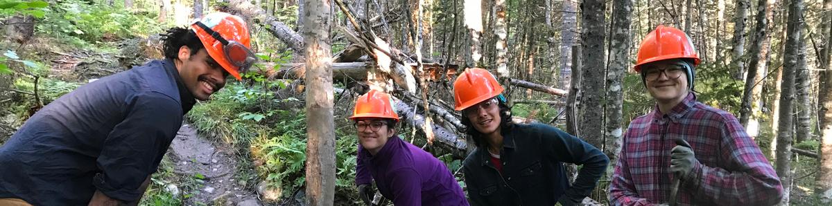 Four people in hardhats smile at the camera