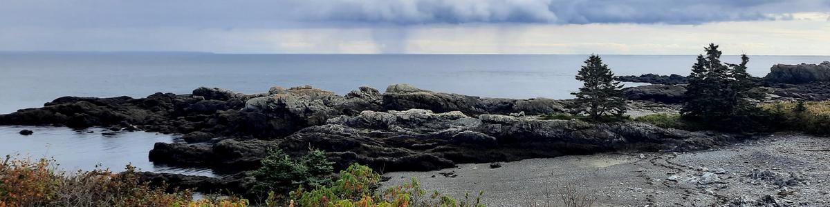 A few of an approaching rainstorm on the ocean and a rocky outcrop