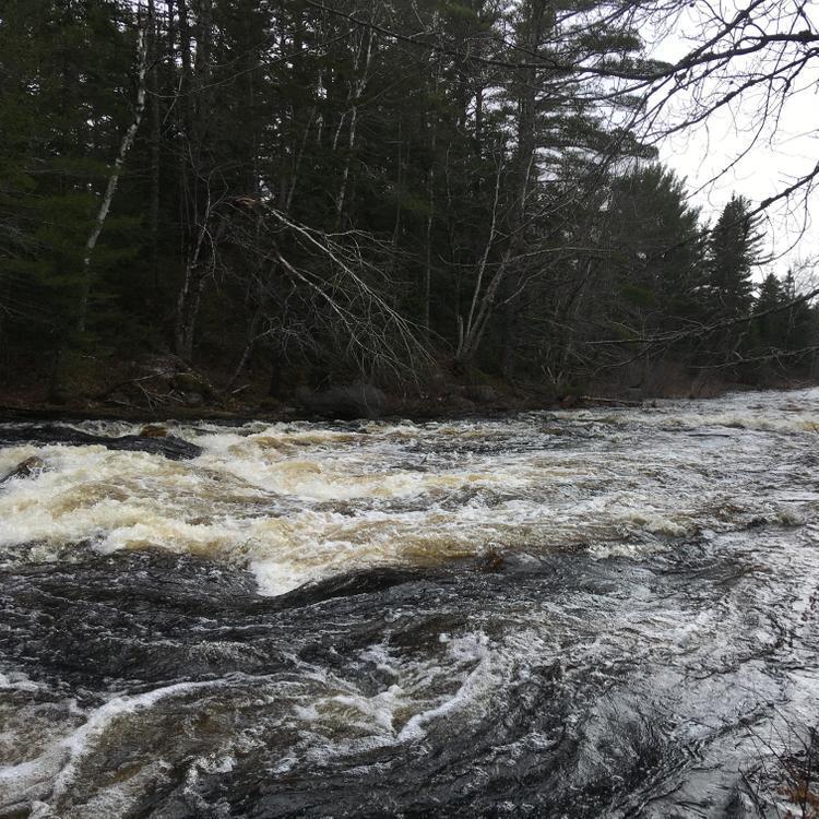 Water roils around rocks in a large rapid