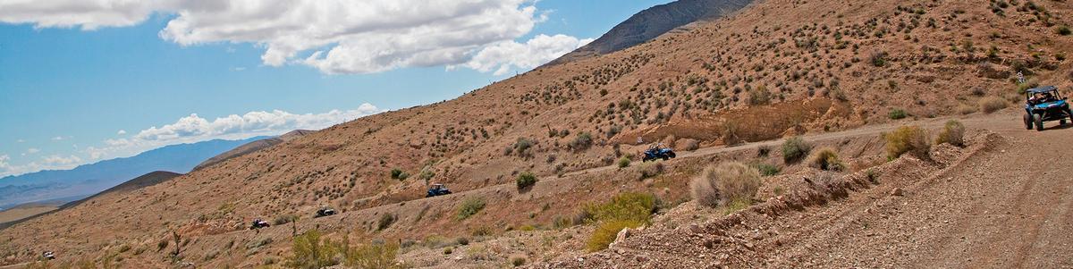 A line of UTVs travels up a road in the Nevada desert