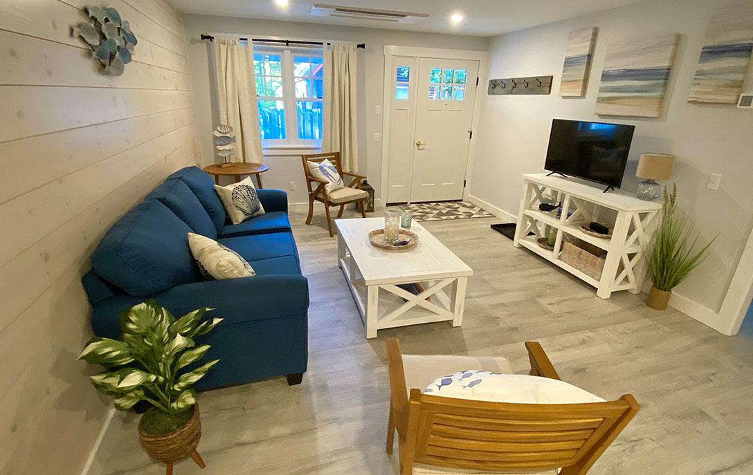 living room in cabin with blue couch and chair and white table and tv