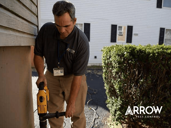 termite control tech outside new jersey home drilling to apply liquid termite treatment