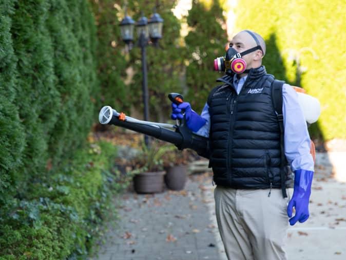 pest control tech performing a mosquito and tick reduction treatment service outside a new jersey home