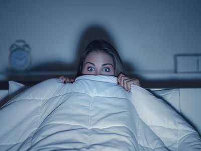 woman hiding her face behind a blanket