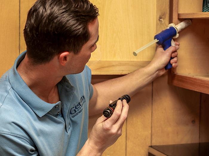 pest control technician treating kitchen for ants