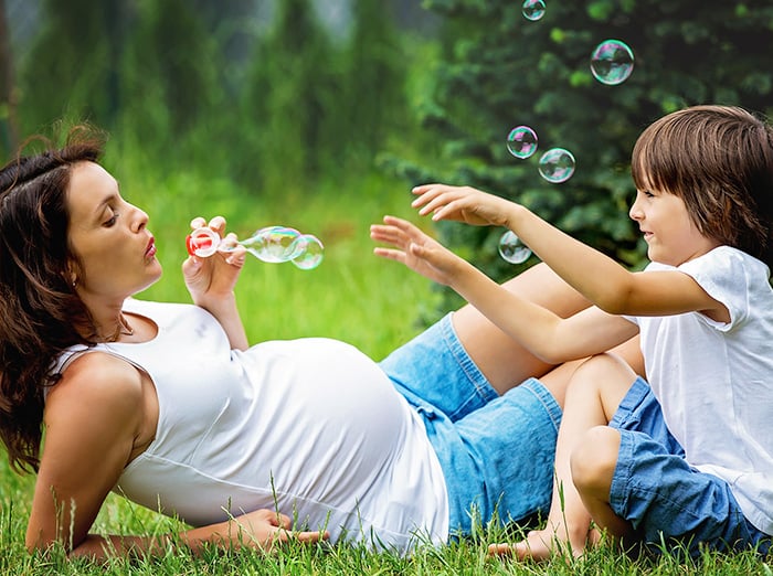 pregnant woman and son playing outside summertime