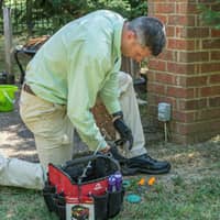 all-american termite technician outside a home