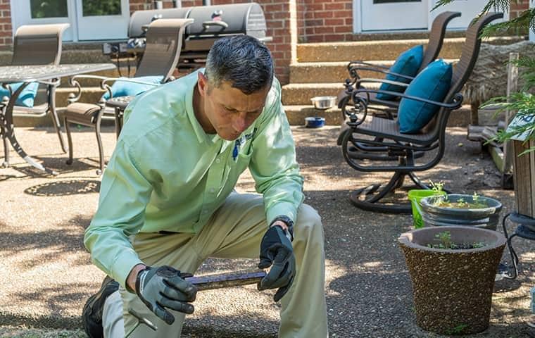 a professional pest control technician treating a tennessee home for termites on a sunny spring day