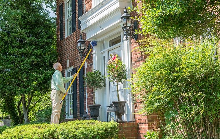 brentwood pest control technician removing spider webs