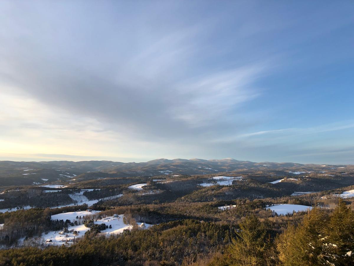 A landscape view from the top of Wright's Mountain shows the valley at golden hour and the sky half covered by clouds.