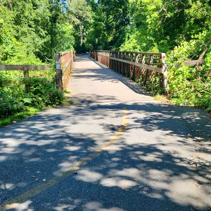 Paved trail leading to a sturdy bridge with railings