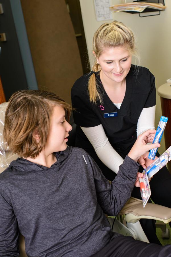 Jessica offers toothbrushes to a patient