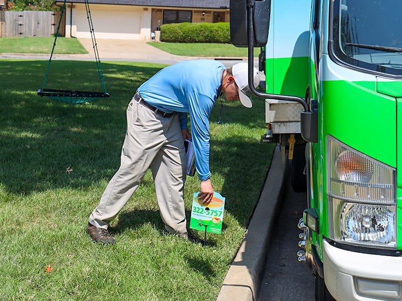 tulsa lawn care pro placing yard sign